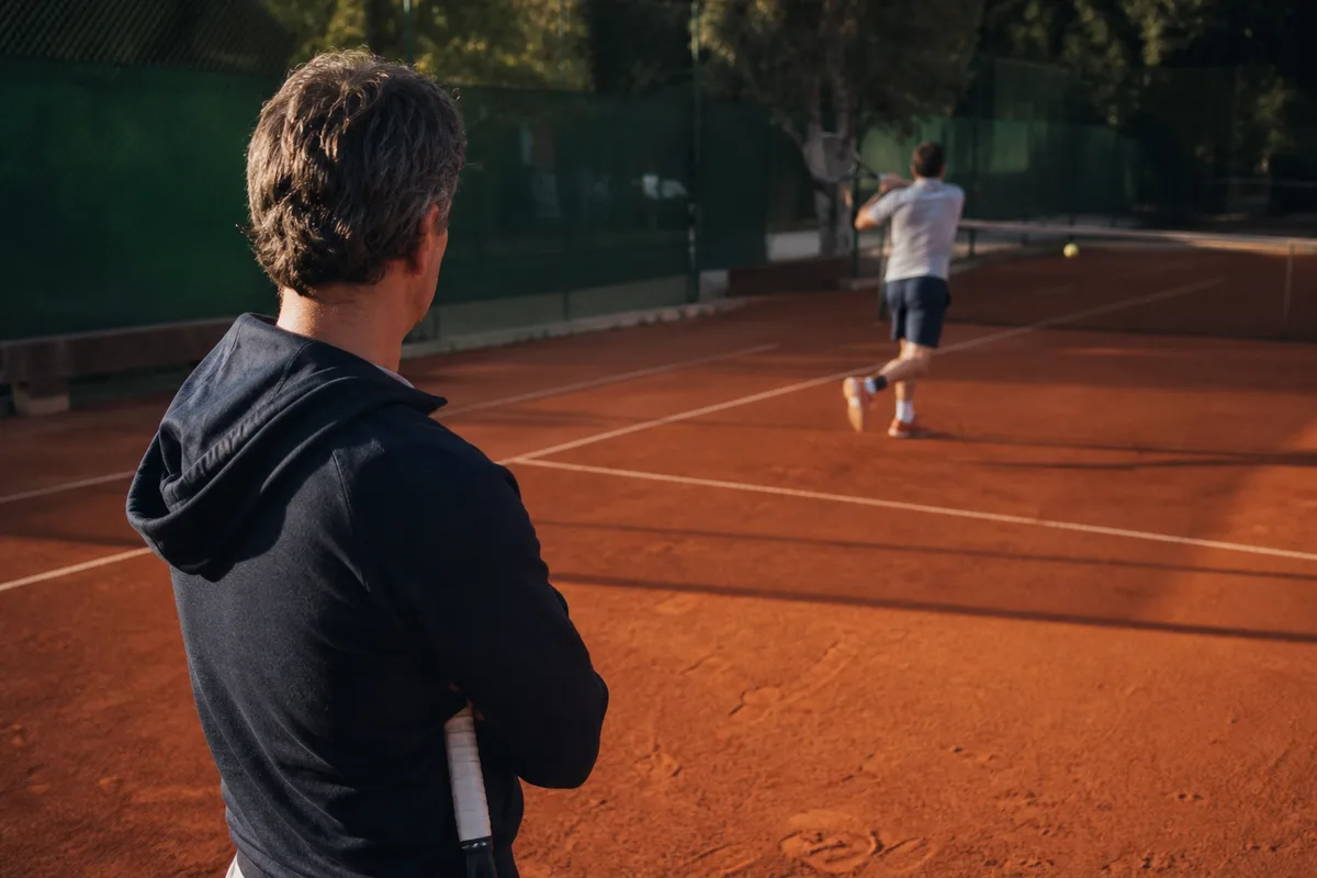 Entraineur de tennis observant le geste d un joueur depuis le bord du court